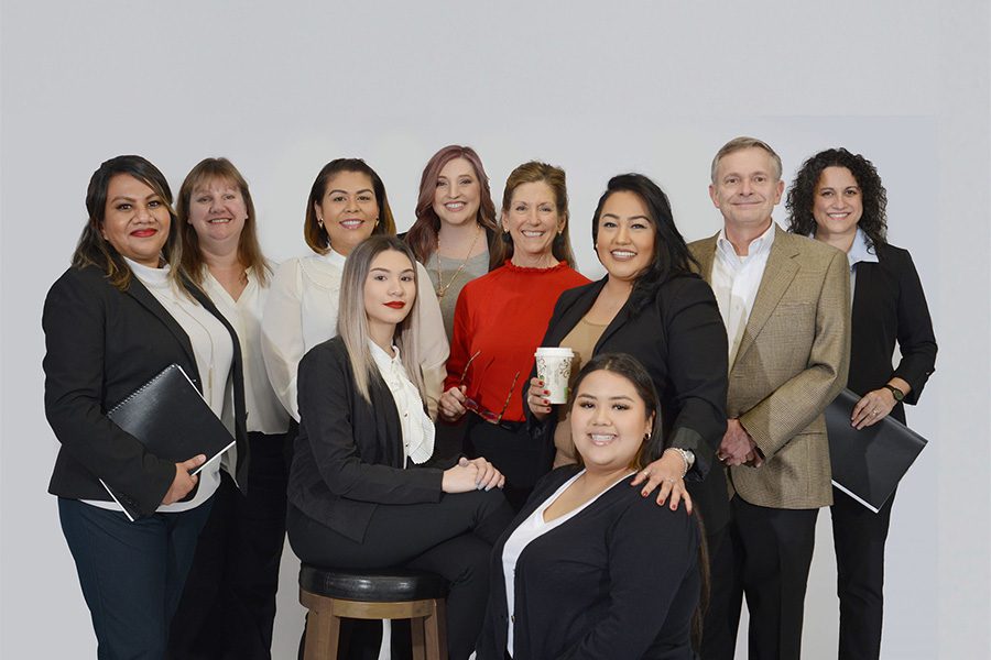 About Our Agency - Portrait of Smiling Nolan Group Insurance Team Memebers Behind a Grey Background