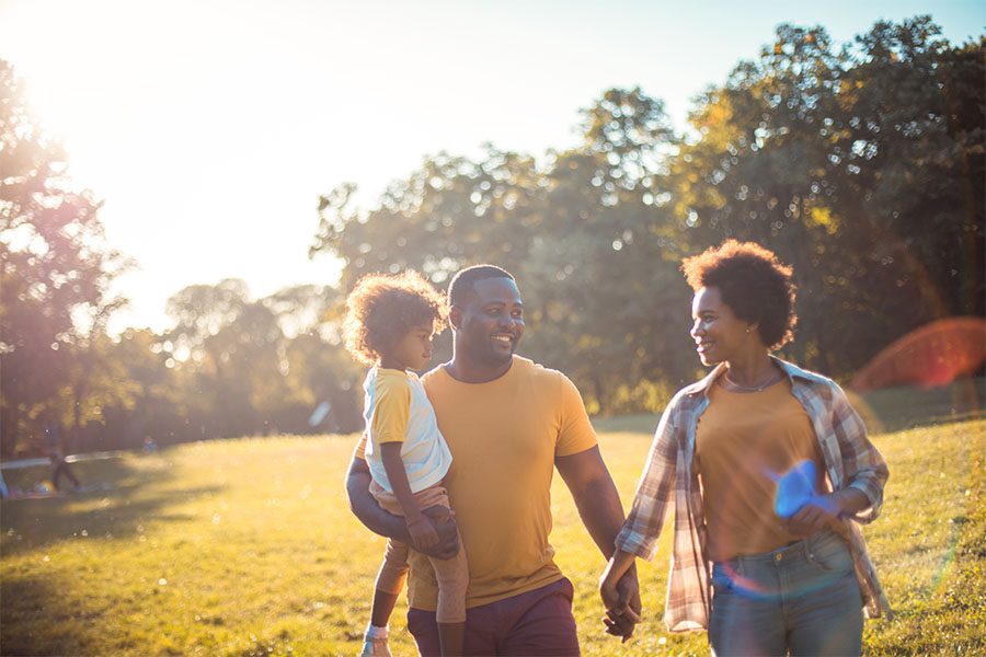 Personal Insurance - Portrait of a Happy Mother and Father Walking in the Park with Their Child on a Sunny Early Morning in the Fall