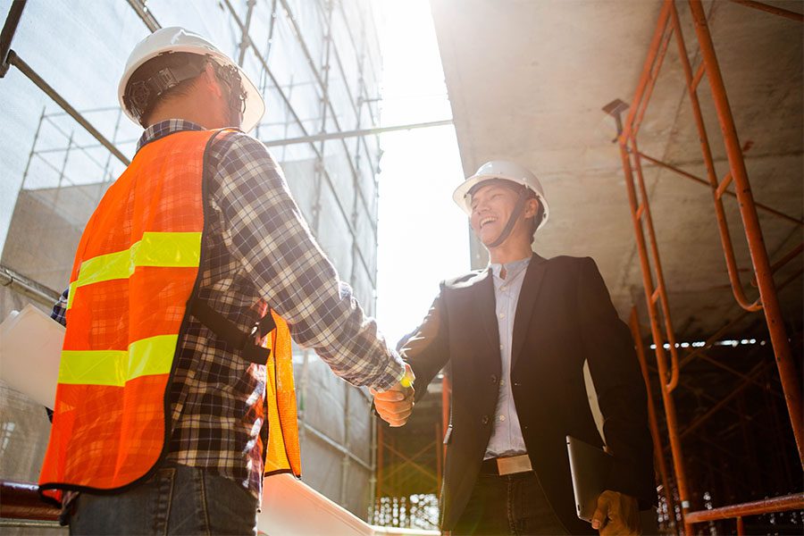 Specialized Business Insurance - Portrait of a Smiling Engineer and Contractor Shaking Hands While on a Commercial Construction Jobsite